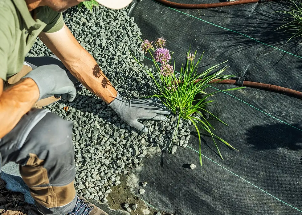 Gartenarbeiter legt Hand auf Kies